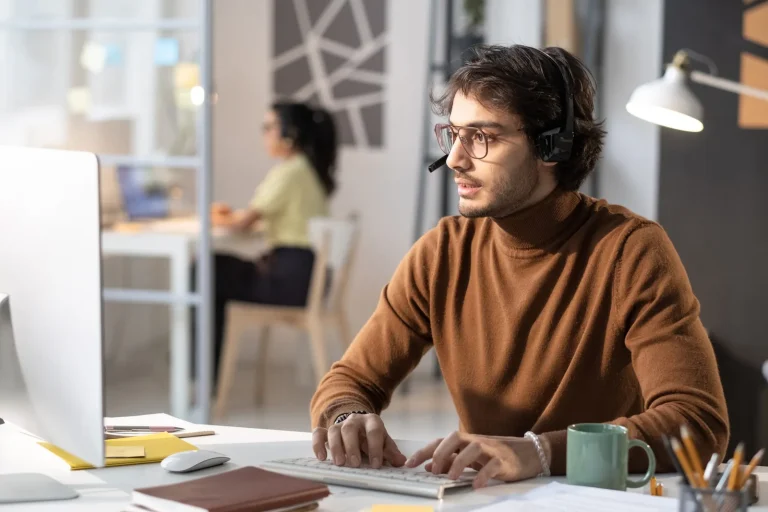Joven con gafas trabaja en un portátil en una oficina compartida